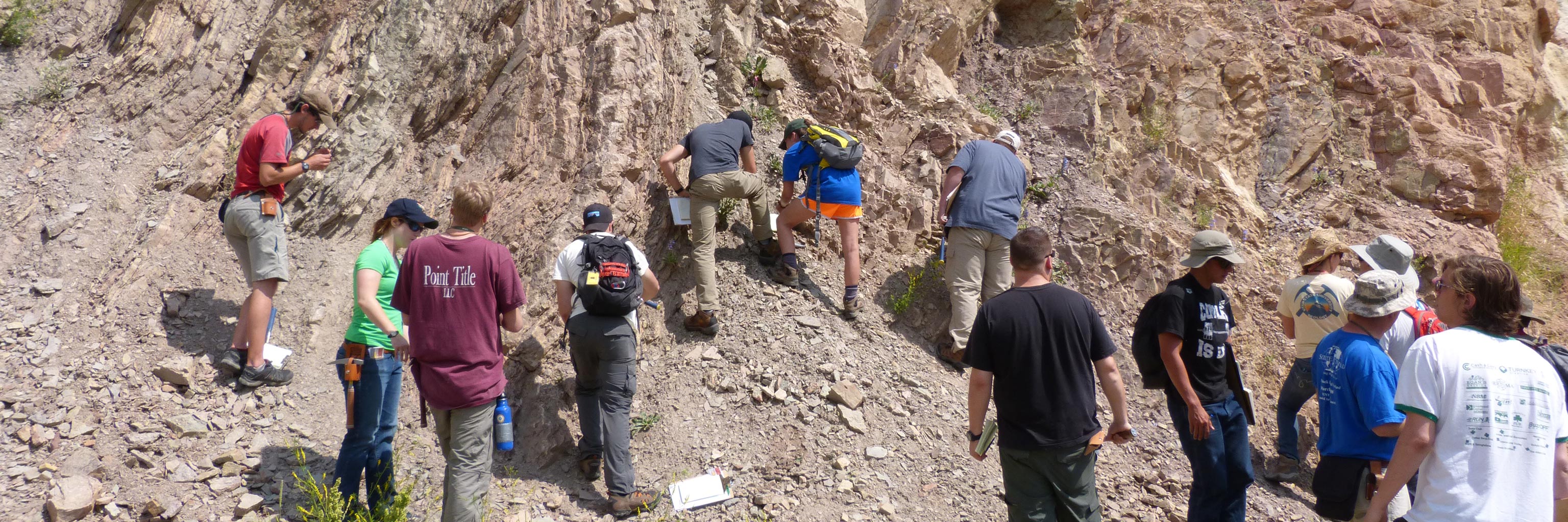 students picking through rocks on a ridge