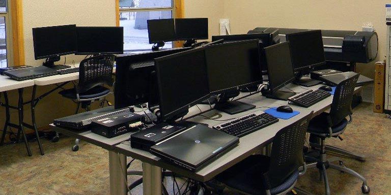 laptops on desks with a large format printer